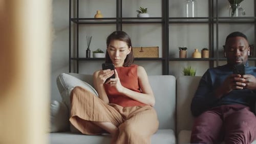 Woman and Man Use Phones on Couch