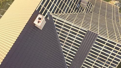 Aerial view of unfinished house with wooden roof structure covered with metal tile sheets under