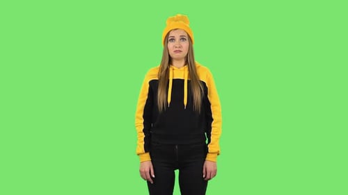 Chica moderna con sombrero amarillo molesta y comienza a llorar. Pantalla verde