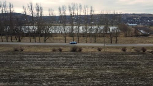 Blue Car Drives Through Rural Landscape