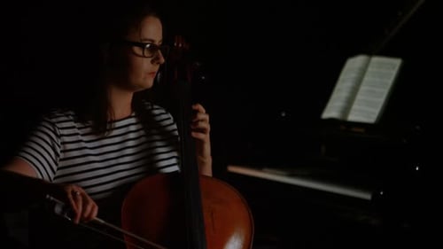 Woman Plays Cello in Dark Room
