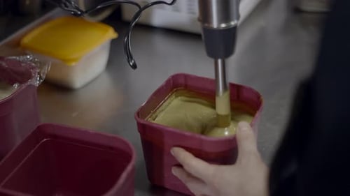 Close Side View of Chef Mixing Sauce with Immersion Blender in Kitchen