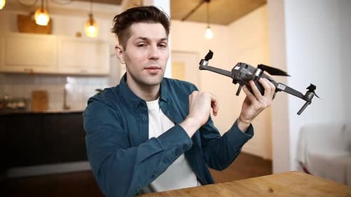 Netter männlicher Blogger, der zu Hause an einem Tisch sitzt, nimmt ein Video vor der Kamera für Abonnenten seines