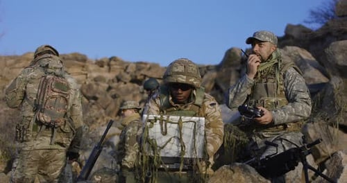 Adults in Camouflage Use Technology in Rocky Terrain