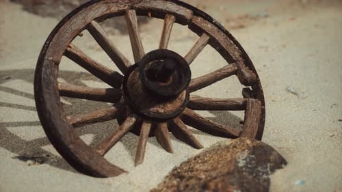 Abandoned Wooden Wagon Wheel in Rustic Sandy Landscape
