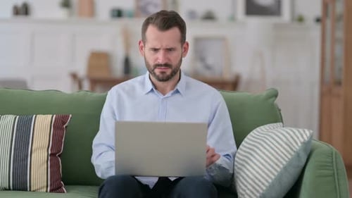 Man Frustrated with Laptop at Home on Couch