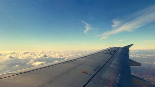 Airplane Wing Flying Over Clouds and Blue Sky