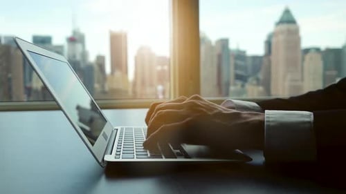 Hands Typing on Laptop in Bright Office