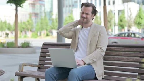 Man on Bench Working on Laptop with Neck Pain