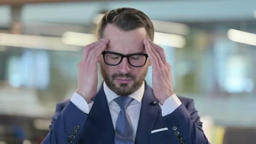 Stressed Businessman with Headache in Office Environment