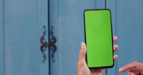 Close Up View of Female Hand Holding Mobilephone and Scrolling Blank Greenscreen . Concept of Mockup