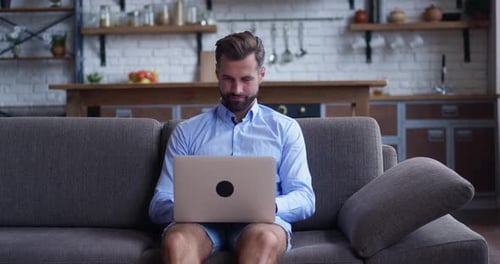 Man Working on Laptop From Couch at Home