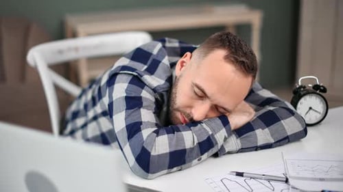 Man Sleeping at Desk with Head on Arms