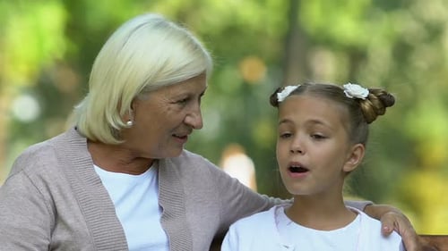 Grandmother and Granddaughter Sitting and Happily Talking in Park, Family