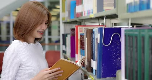 Asian beauty college student reading book in library.