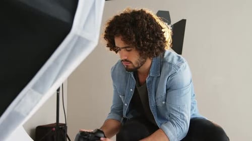 Photographer Adjusting Camera in Studio Setting