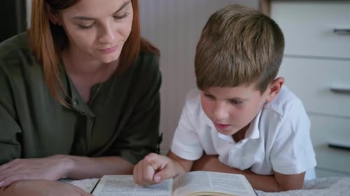 Woman and Boy Reading a Book Together Indoors