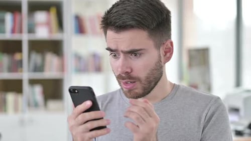 Man Reacts to News on his Mobile Phone