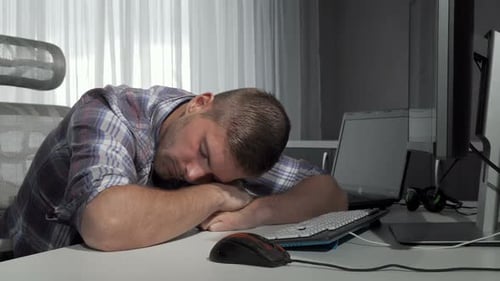 Tired Man Sleeping at Desk in Front of Computer