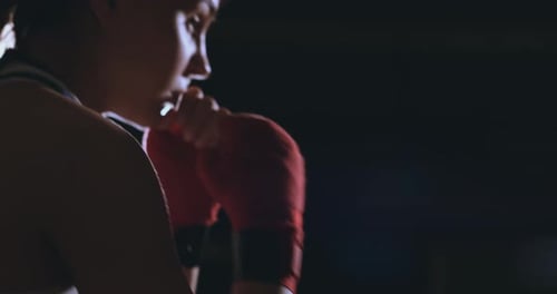 A Beautiful Woman Boxer Trains in a Dark Gym and Works Out Punches in Slow Motion. Side View