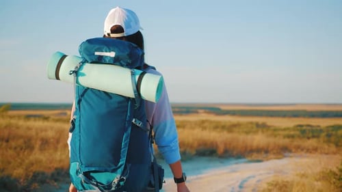 Backpacker Hiking Across Open Rural Landscape on Sunny Day