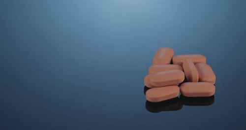 Orange Pills Piled on Reflective Surface