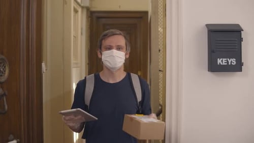 Delivery Man with Face Mask Holds Box and Tablet