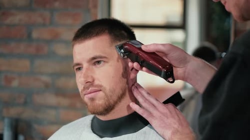 Männlicher Haarschnitt mit Elektrorasierer. Nahaufnahme des Haarschnitts eines Mannes. Männliche Hände Barbier Rasiermann mit
