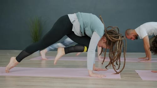 Young Girls and Guy Doing Yoga Practice in Studio on Mats Focused on Recreational Activity