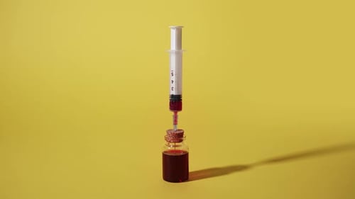 Une seringue prélève du sang dans un flacon en verre