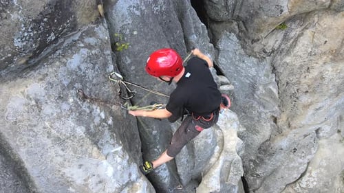 Determined Climber Clambering Up Steep Wall of Rocky Mountain