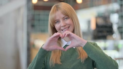 Woman Smiling and Making Heart Shape with Hands