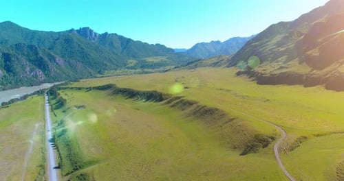 Aerial Rural Mountain Road and Meadow at Sunny Summer Morning. Asphalt Highway and River.