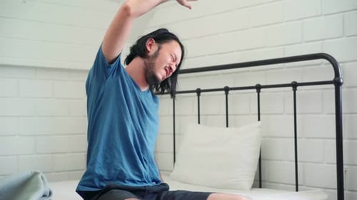 Adult Stretching on Bed in Bright Bedroom