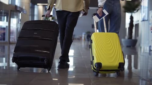 Couple Rolling Luggage Through Airport Terminal