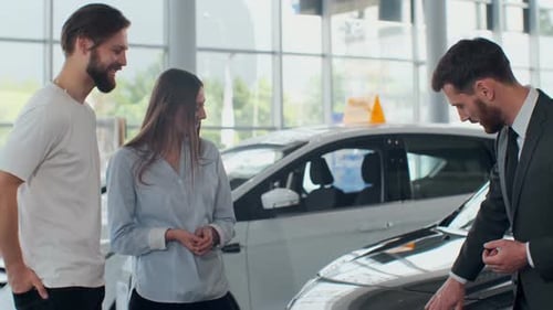 Couple Discussing Car with Salesman in Dealership Showroom