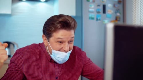 Man Celebrates at His Computer Wearing a Face Mask