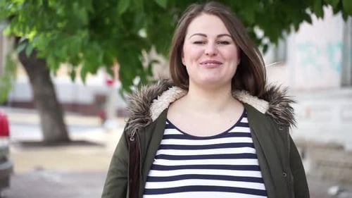 Plus size presenter talking and looking at camera in the street.