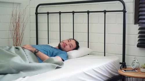 Man Wakes Up and Stretches in Bed