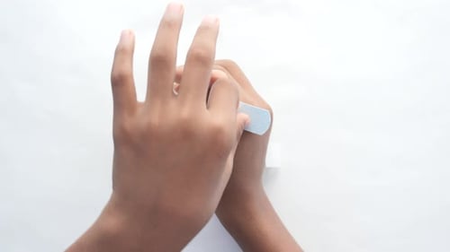 Hands Applying Blue Bandage to Thumb