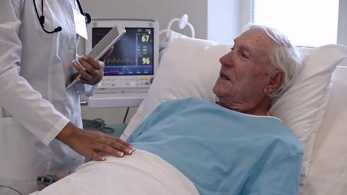 Senior Patient Talking to Nurse in Hospital Ward