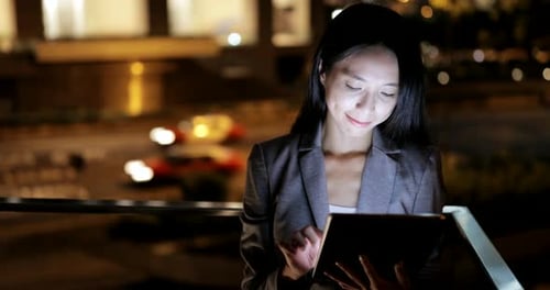 Woman Using Tablet Outside at Night