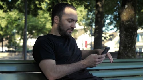 Man Using Smartphone on Park Bench