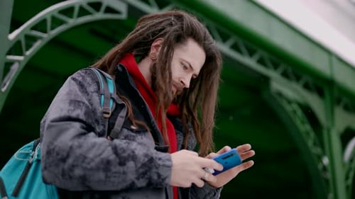 Young Adult with Dreadlocks Using Smartphone in City