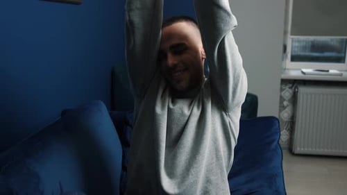 Man Stretching and Relaxing on Blue Couch