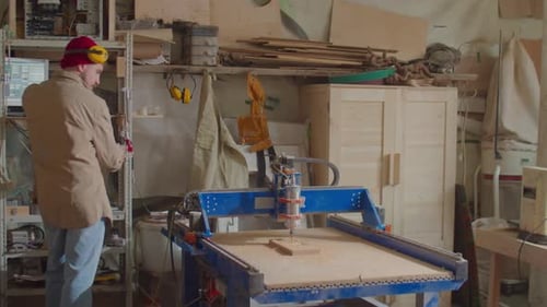 Man Operating Woodworking CNC Machine with Computer