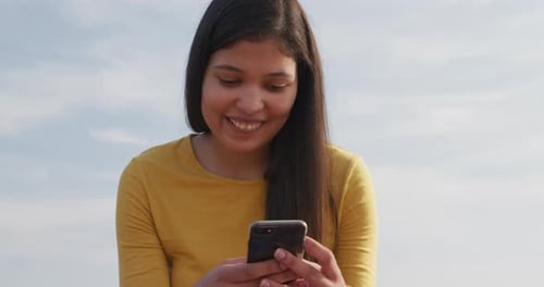 Woman Smiling Using Phone at Beach on Sunny Day