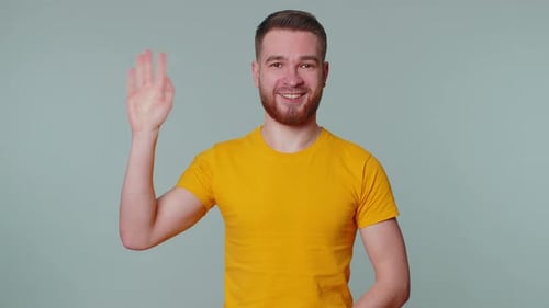 Man in Yellow Shirt Waves Hello to Camera