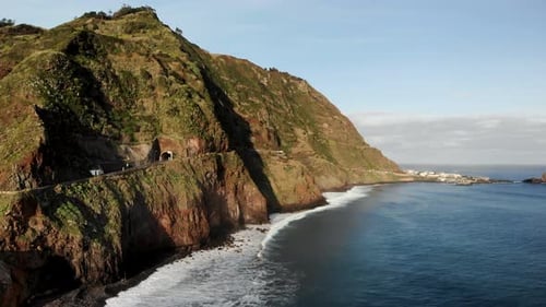 Waves Crashing Into Rocky Beach and Road Tunnel in Mountain Side