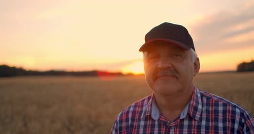 Close-up Portrait of a Farmer in a Cap at Sunset Looking Directly Into the Camera